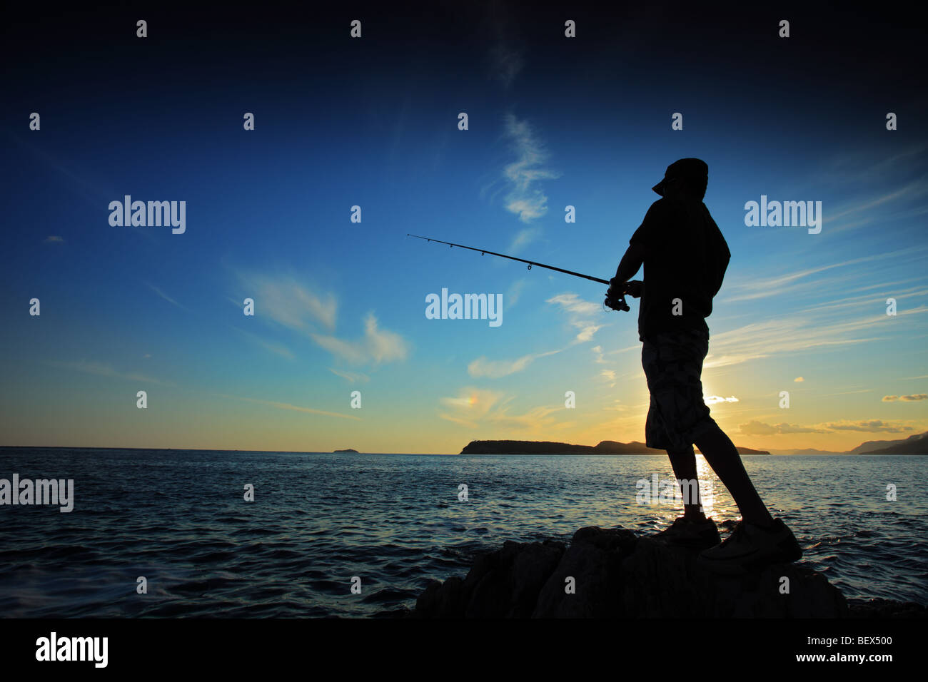 L'homme pêche sur le coucher du soleil Banque D'Images