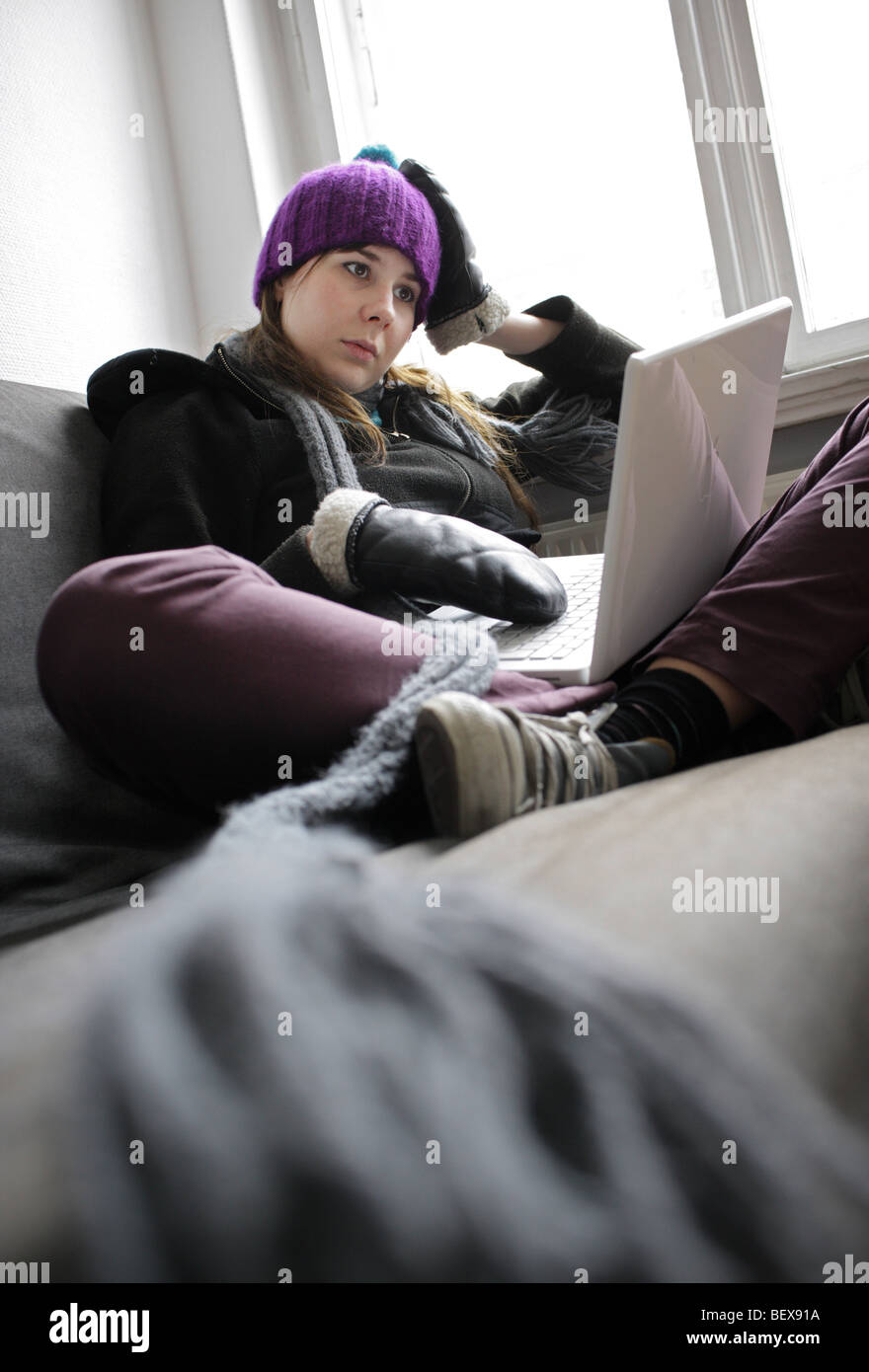 Chauffage économie côtes, jeune femme à la maison portant une casquette et des gants . Banque D'Images