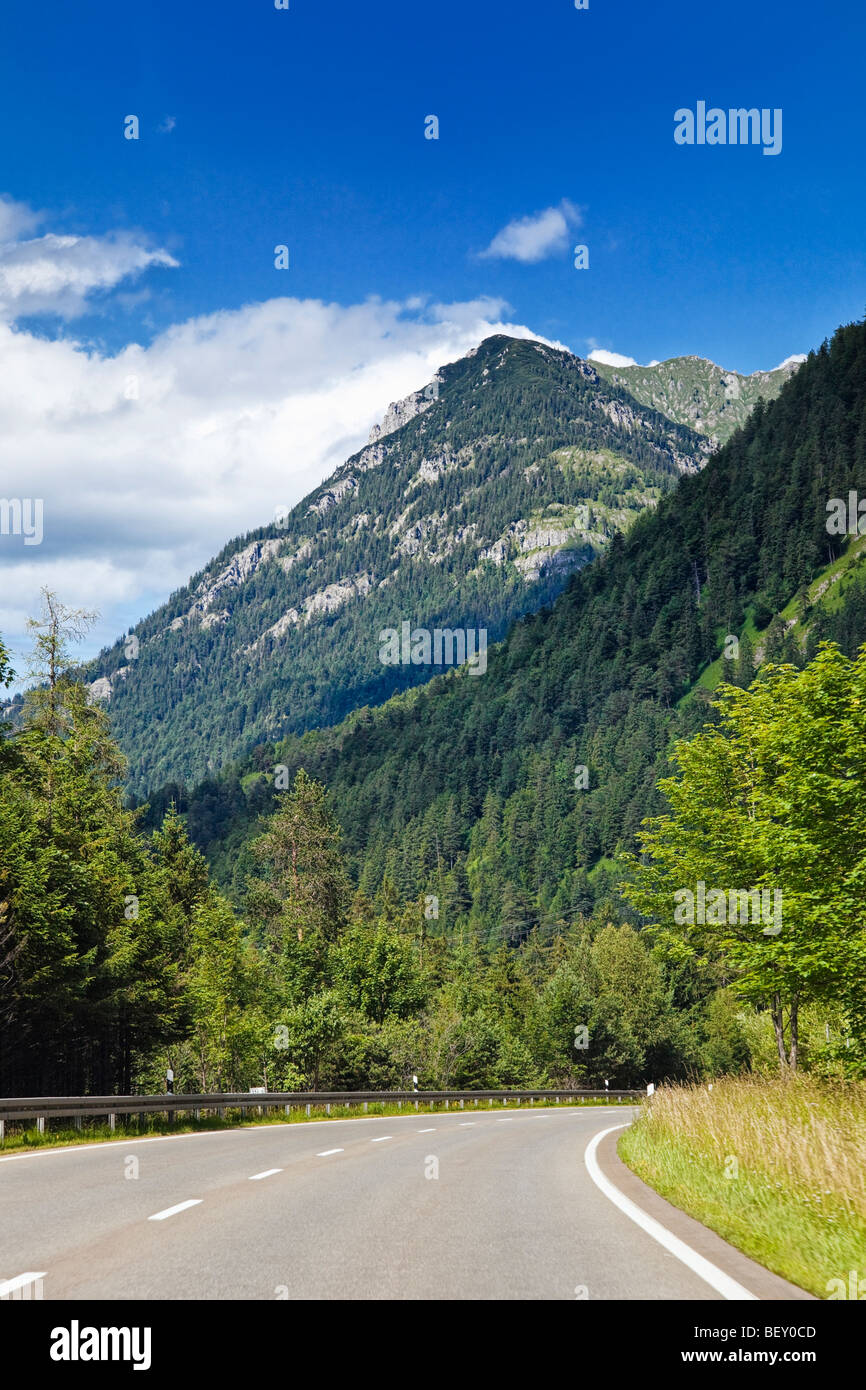 Route à travers une forêt vide vers les Alpes bavaroises, l'Allemagne, de l'Europe montagnes Banque D'Images