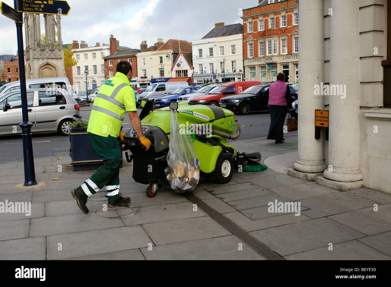 À l'aide d'un dispositif de marche derrière la chaussée et balayeuse sur le trottoir dans le centre-ville de Devizes Wiltshire England UK Banque D'Images