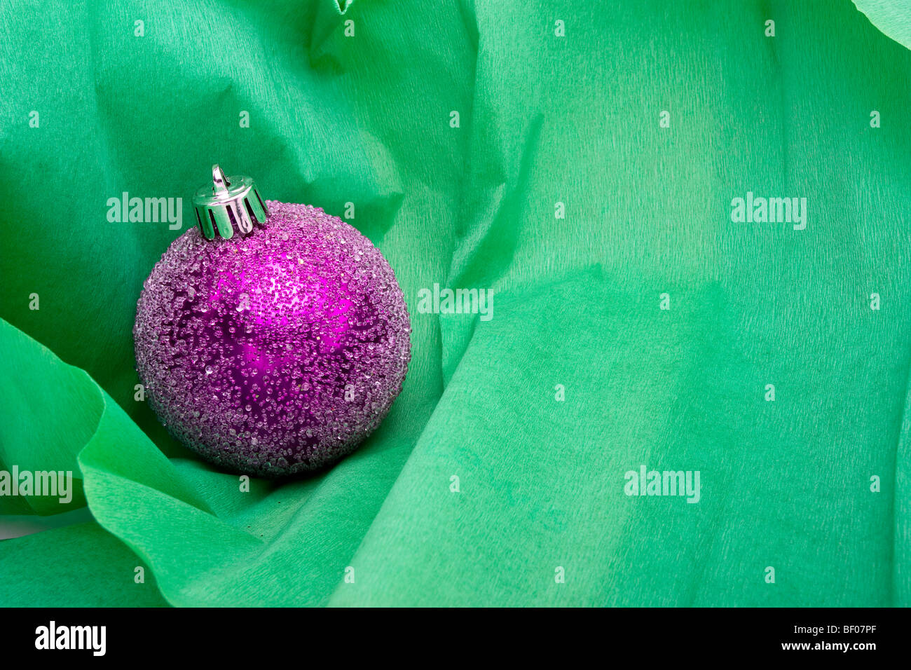 Pink Christmas bauble decoration sur fond de papier crêpe vert Banque D'Images