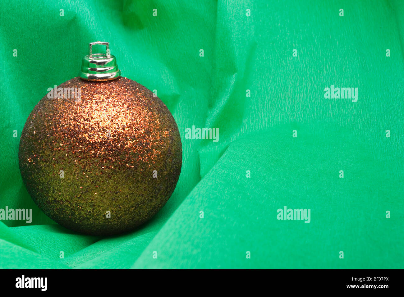 Golden Christmas bauble decoration sur fond de papier crêpe vert Banque D'Images