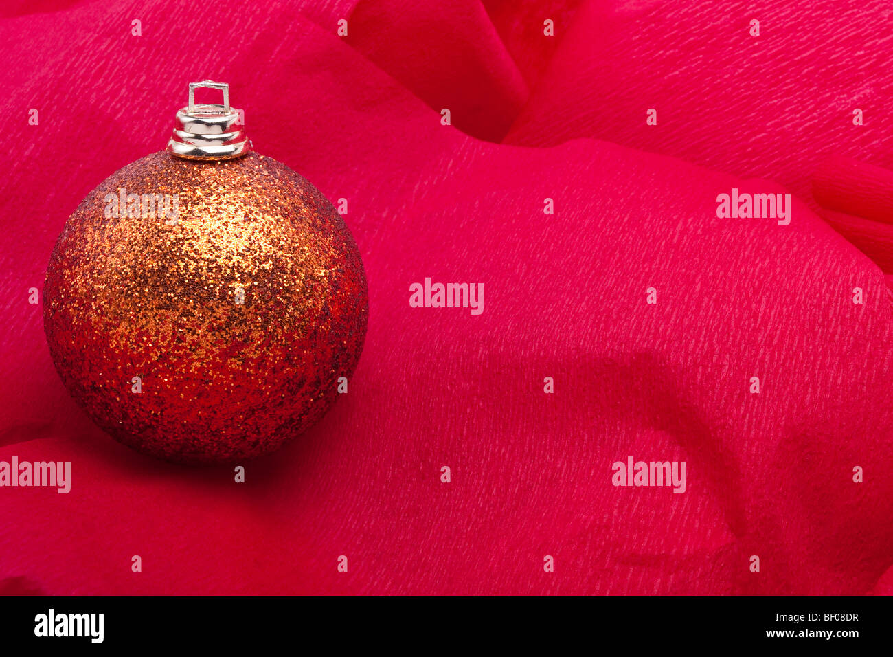 Golden Christmas bauble decoration sur fond papier crépon rouge Banque D'Images