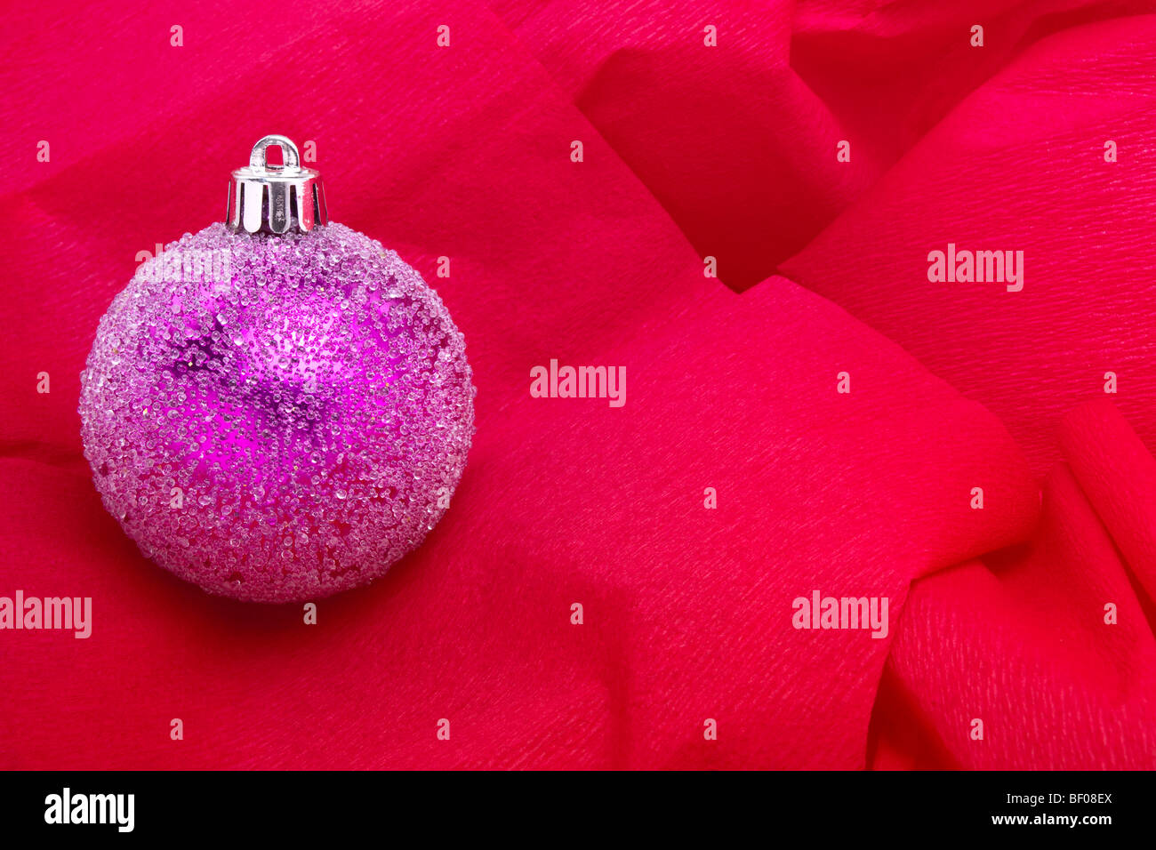 Pink Christmas bauble decoration sur fond papier crépon rouge Banque D'Images