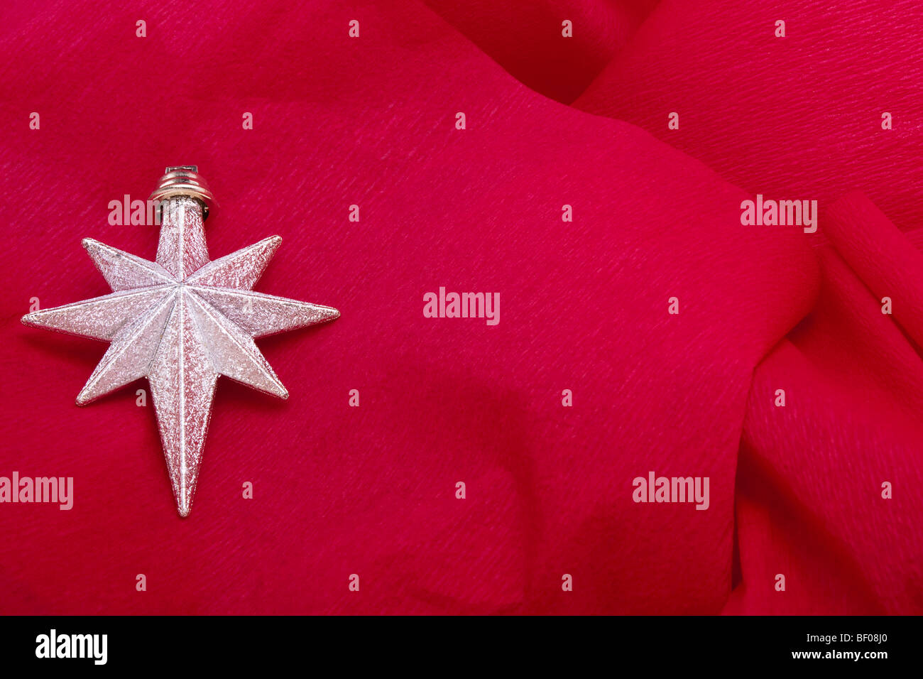 Décoration étoile de Noël d'argent sur fond de papier crêpe rouge Banque D'Images
