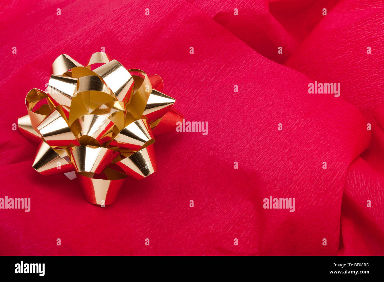 Noël Décoration bow or sur fond de papier crêpe rouge Banque D'Images