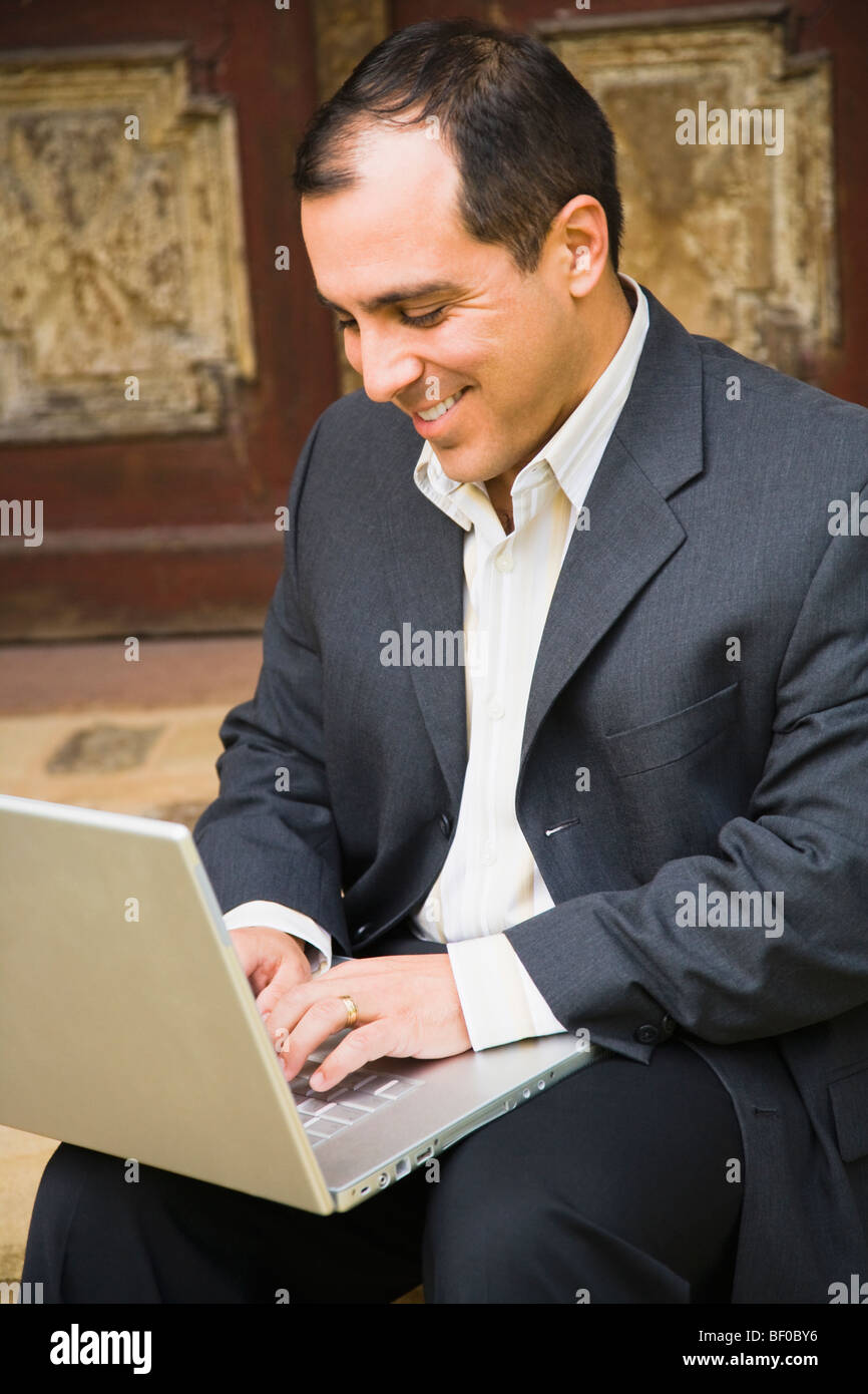 L'homme travaillant sur un ordinateur portable en face d'une porte Banque D'Images