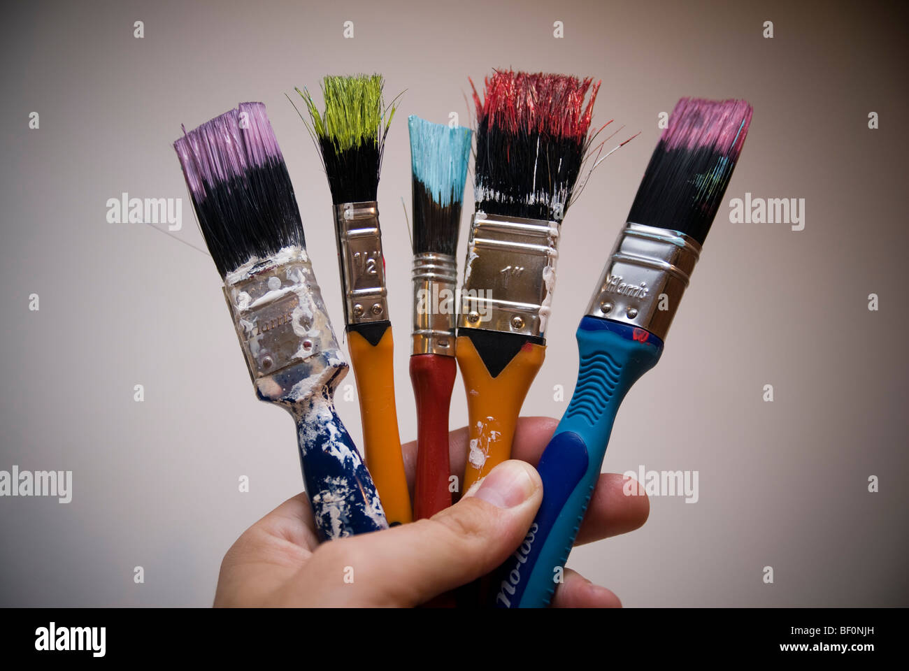 Une poignée de pinceaux colorés avec de la peinture de couleur vive. Banque D'Images