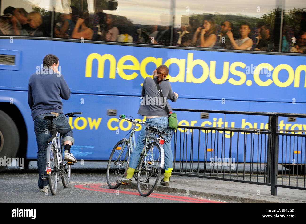 Les cyclistes masculins et féminins en attente de bus touristique pour passer à la jonction central London England UK Banque D'Images
