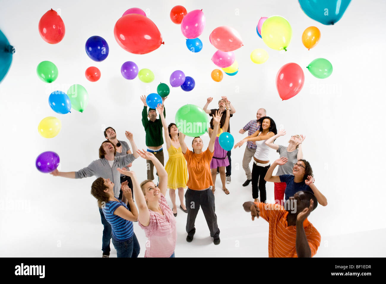 Un groupe d'hommes et de femmes pour atteindre les ballons flottant Banque D'Images