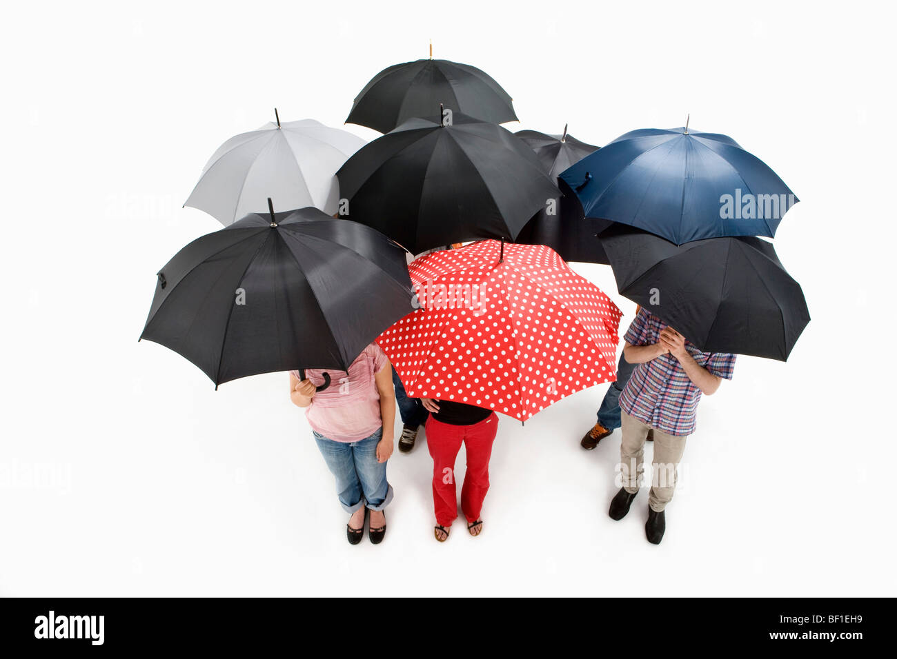 Groupe d'hommes et de femmes debout sous les parasols Banque D'Images