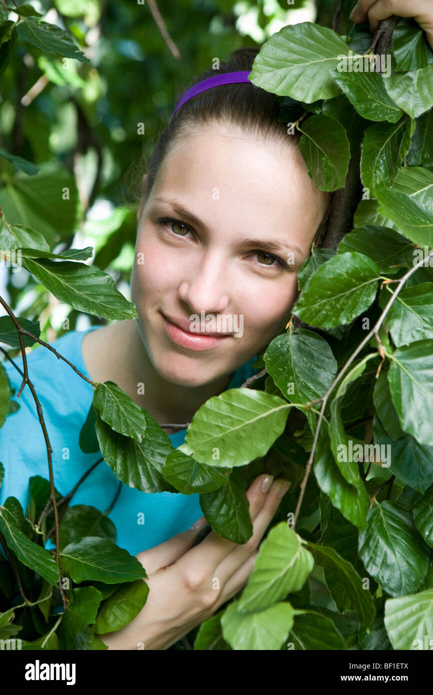 Portrait of a young woman's face encadrée par des feuilles Banque D'Images