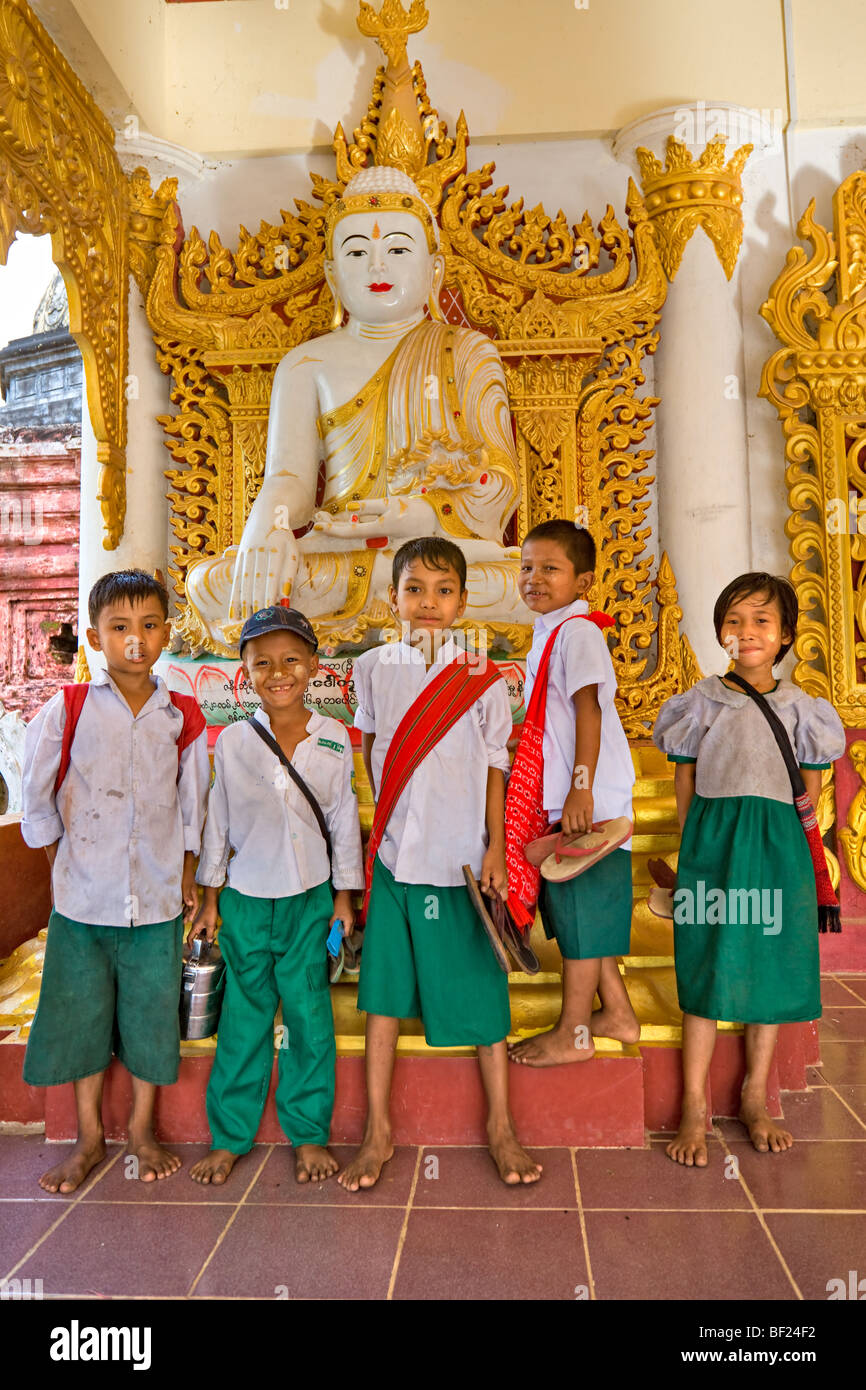 Pour les enfants de l'école présentant sous une statue de bouddha, Bago, le Myanmar. Banque D'Images