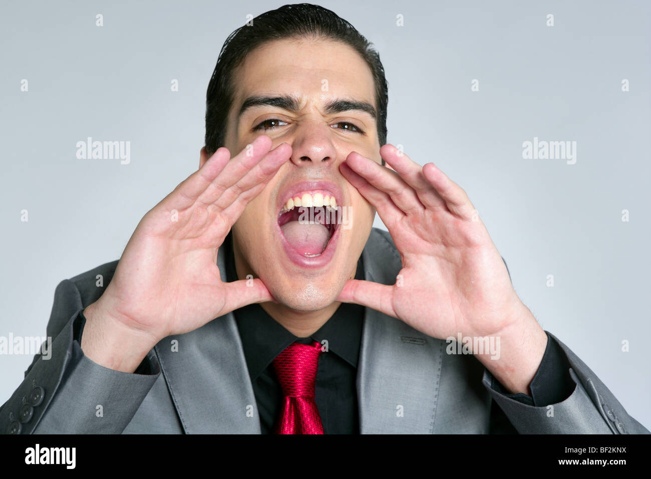 Businessman mains ouvertes crier pour appareil photo sur fond gris Banque D'Images