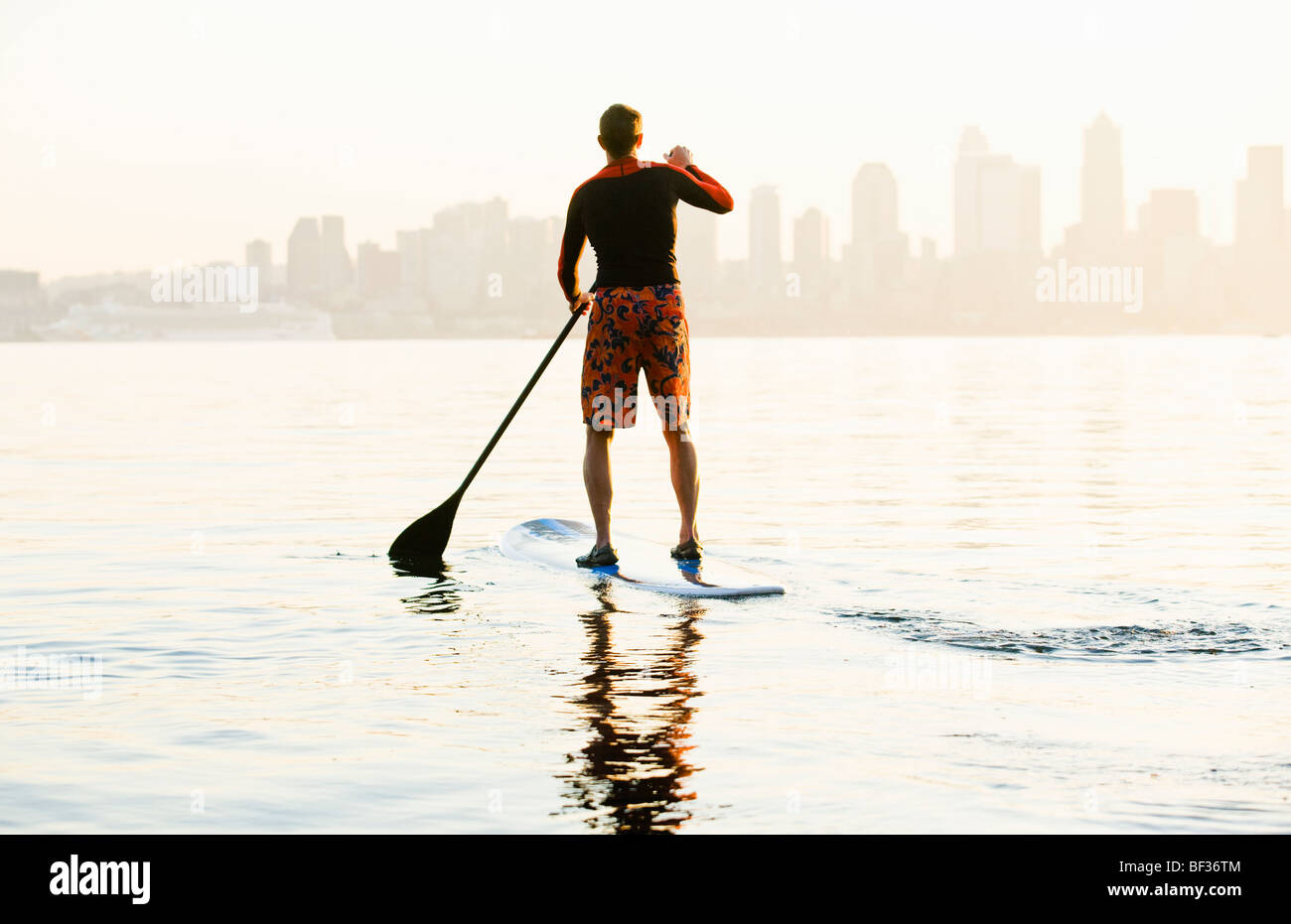 Un homme paddling sur son stand-up paddle board sur la baie Elliott avec le Seattle Space Needle en arrière-plan. Banque D'Images