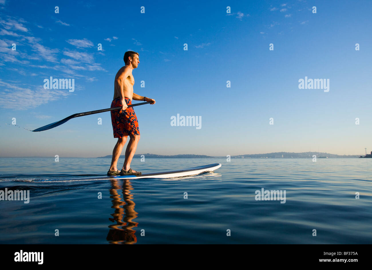 Fin des années 30 un homme de race blanche sur un stand up paddle board sur le Puget Sound près de Seattle, WA. Banque D'Images