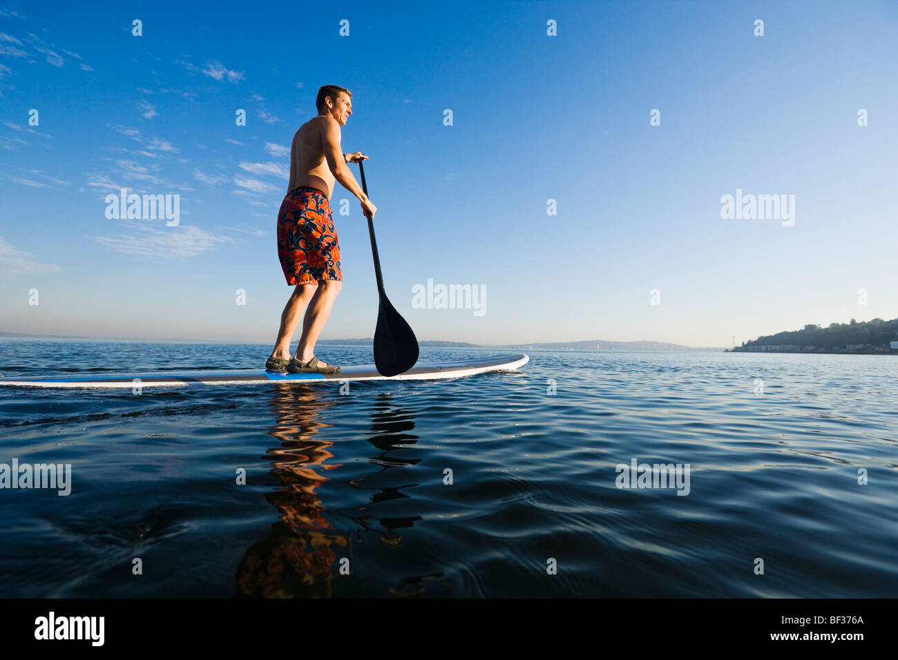 Fin des années 30 un homme de race blanche sur un stand up paddle board sur le Puget Sound près de Seattle, WA. Banque D'Images
