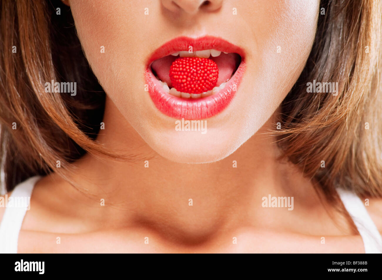 Close-up d'une framboise dans une bouche de femme Banque D'Images