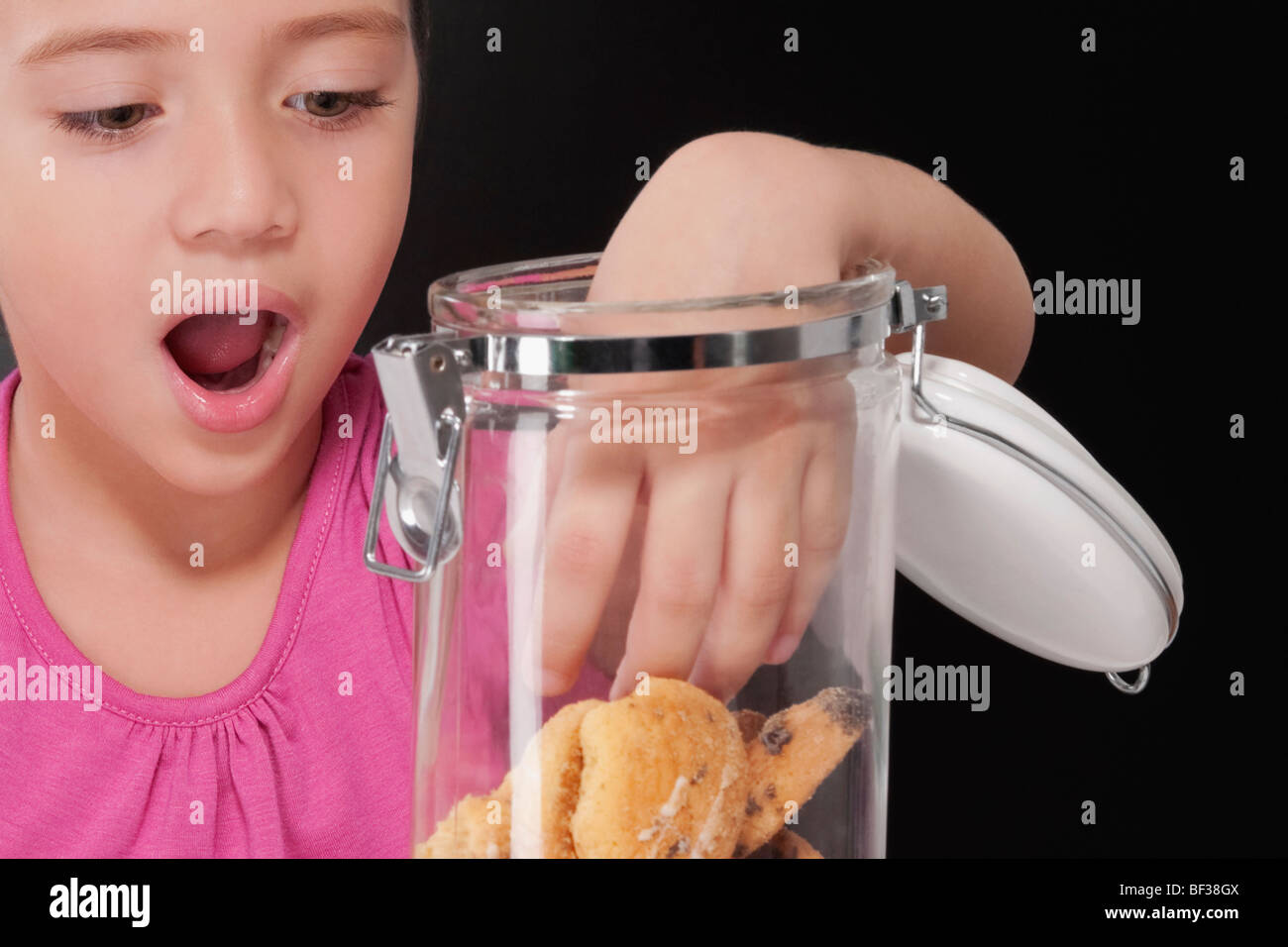 Fille de mettre sa main dans un cookie jar Banque D'Images