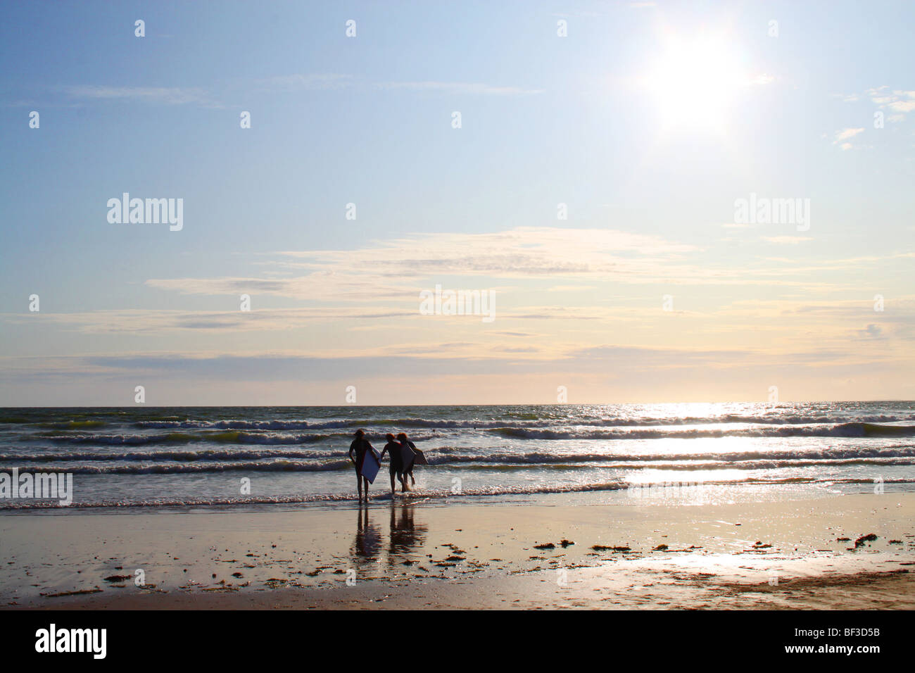 Les surfeurs en marche dans la mer, Rhossili Bay, la péninsule de Gower, au Pays de Galles Banque D'Images