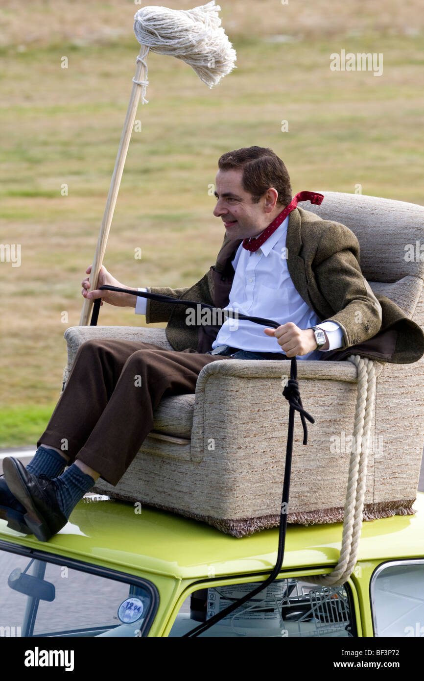 Rowan Atkinson, alias Mr Bean, rides un fauteuil sur le toit d'une Mini 1000 à Goodwood Revival meeting, Sussex, UK. Banque D'Images