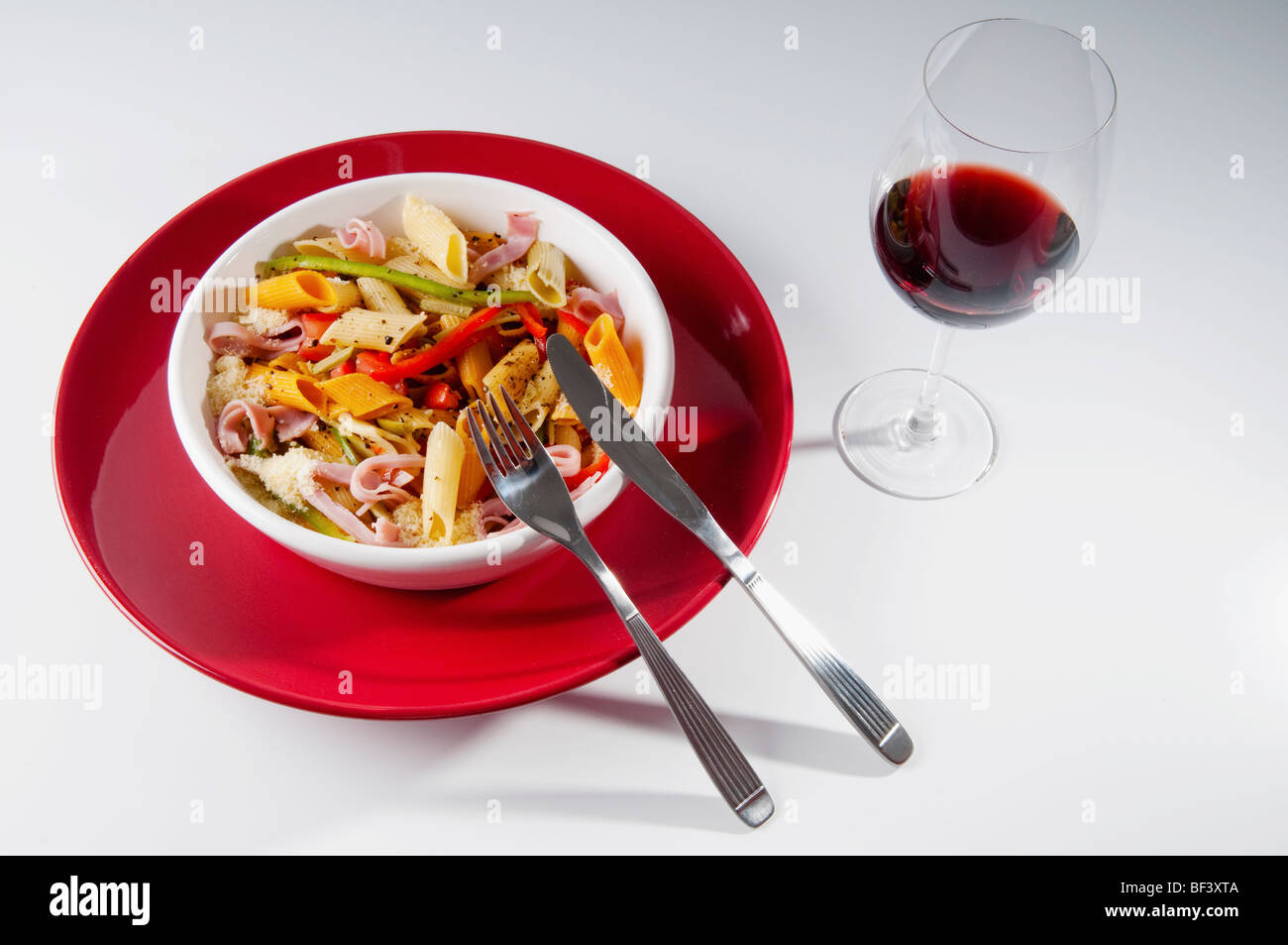 Portrait d'un bol de pâtes Penne et Jambon salade avec verre de vin Banque D'Images