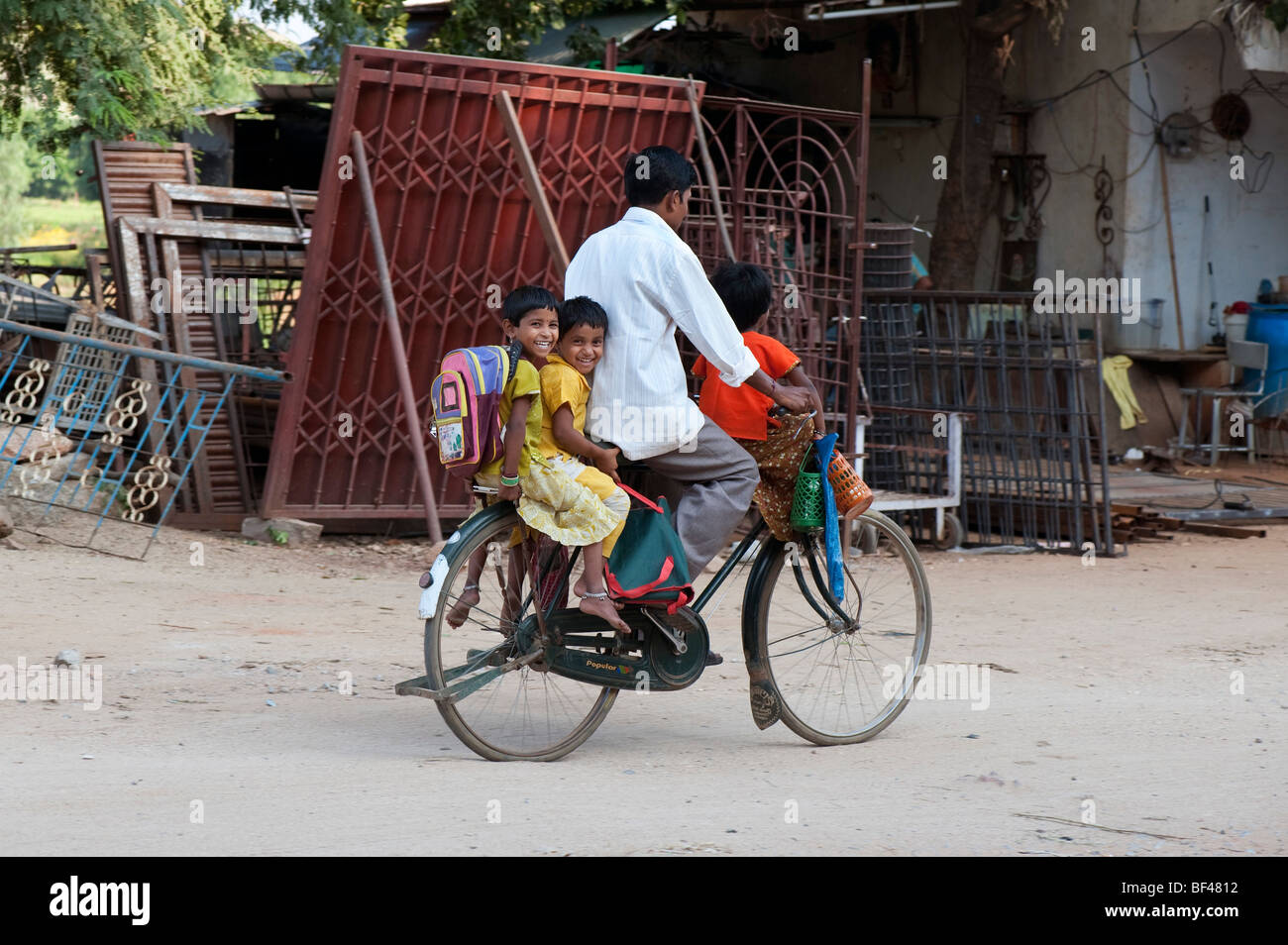 Père indien de prendre ses trois enfants à l'école à bicyclette Banque D'Images