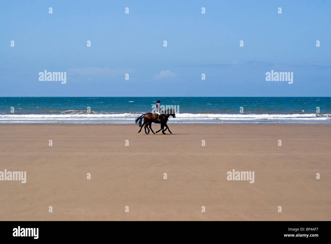 Deux chevaux et cavaliers sur Kenfig Sands près de Porthcawl, dans le sud du Pays de Galles, Royaume-Uni. Banque D'Images