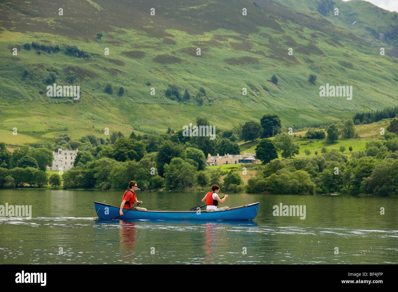Vue latérale de 2 jeunes adultes du caucase pagayant un canot canadien sur un Loch Earn déserté, dans le Perthshire, en Écosse. ROYAUME-UNI. Banque D'Images