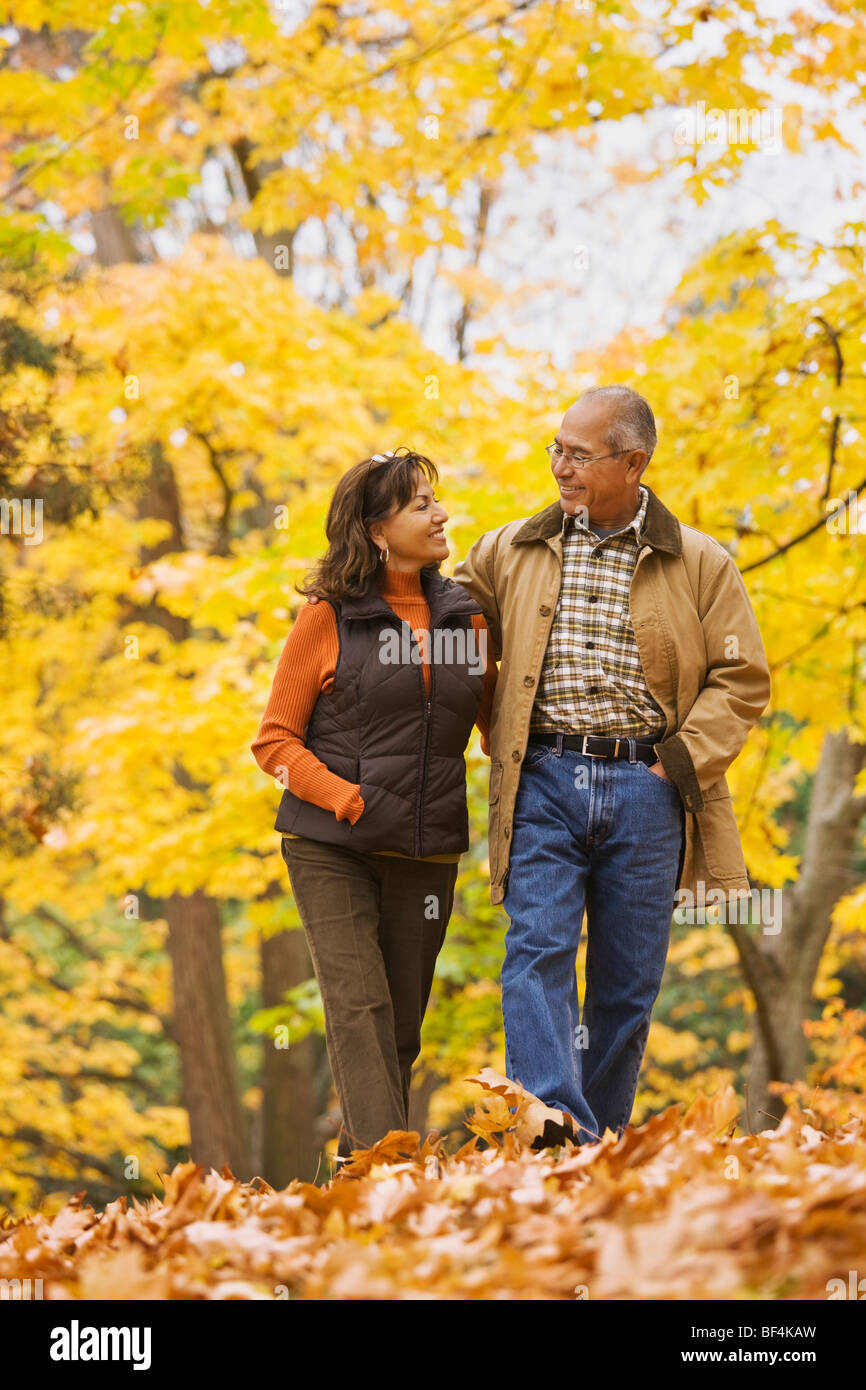 Hispanic couple en train de marcher dans les feuilles d'automne Banque D'Images