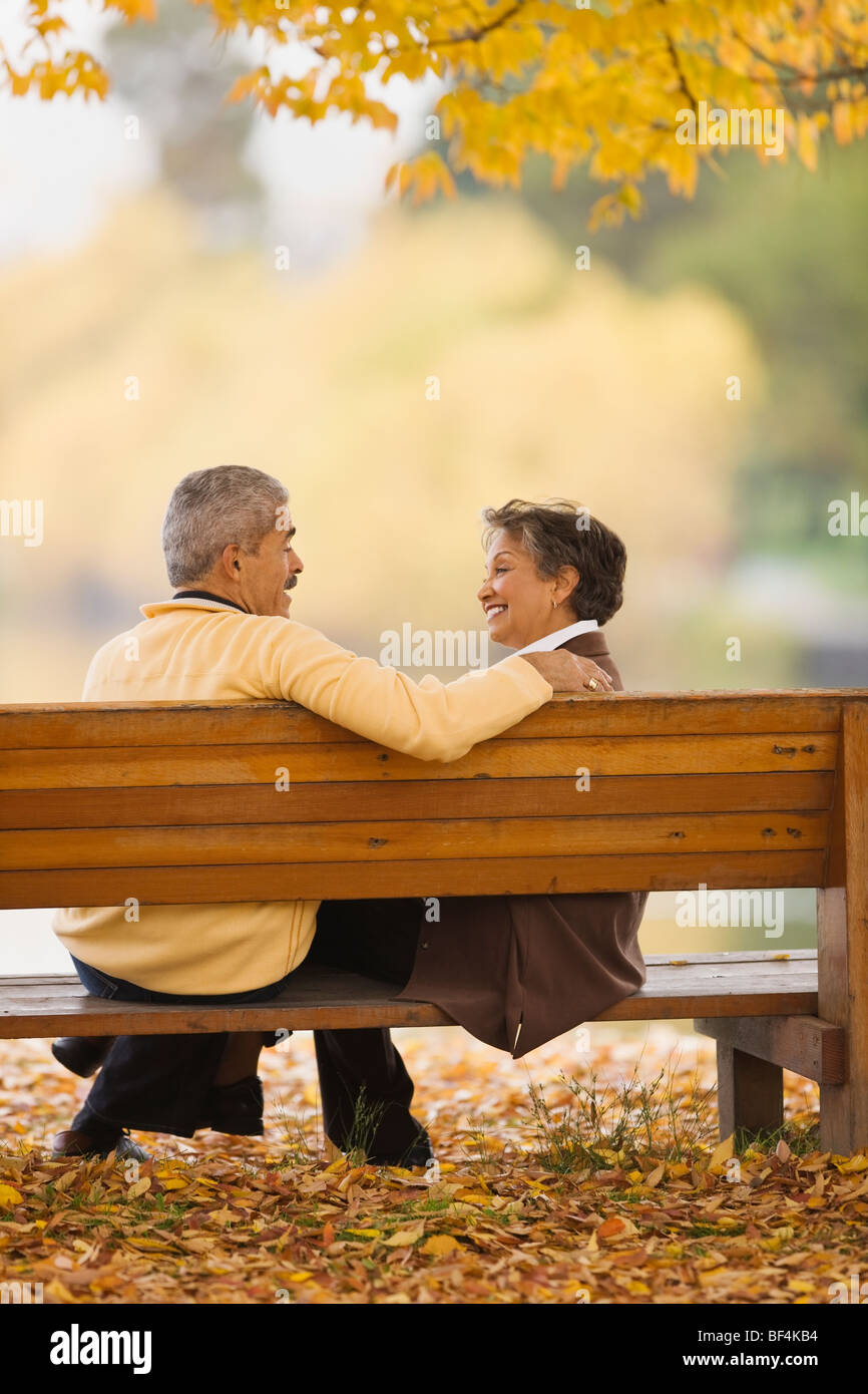 African couple assis sur banc de parc en automne Banque D'Images