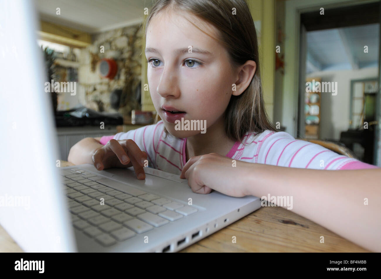 Une fillette de 9 ans à un ordinateur dans la cuisine Banque D'Images