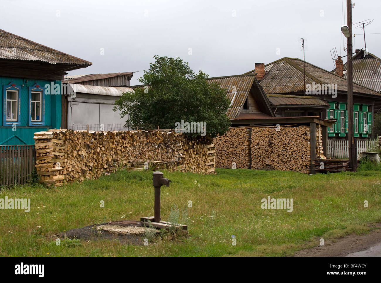 Bois de chauffage empilé et communautaires d'un robinet d'eau par des maisons dans les régions rurales de la ville, de l'Oural, Russie Banque D'Images