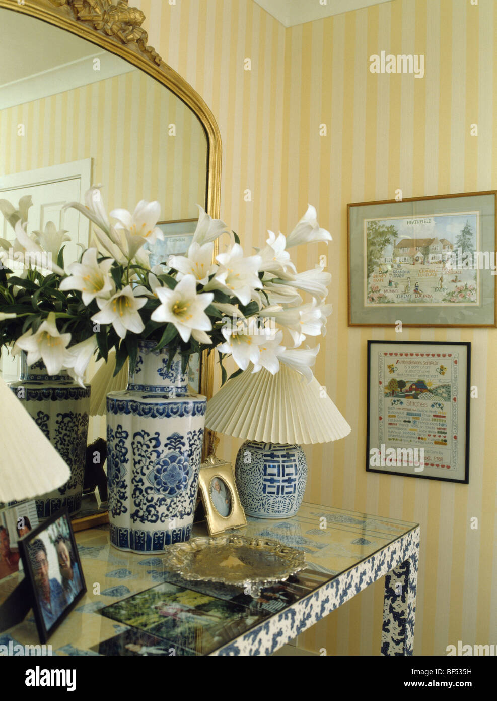 Close-up de lys blancs en bleu +blanc vase chinois sur table console avec lampes crème Banque D'Images