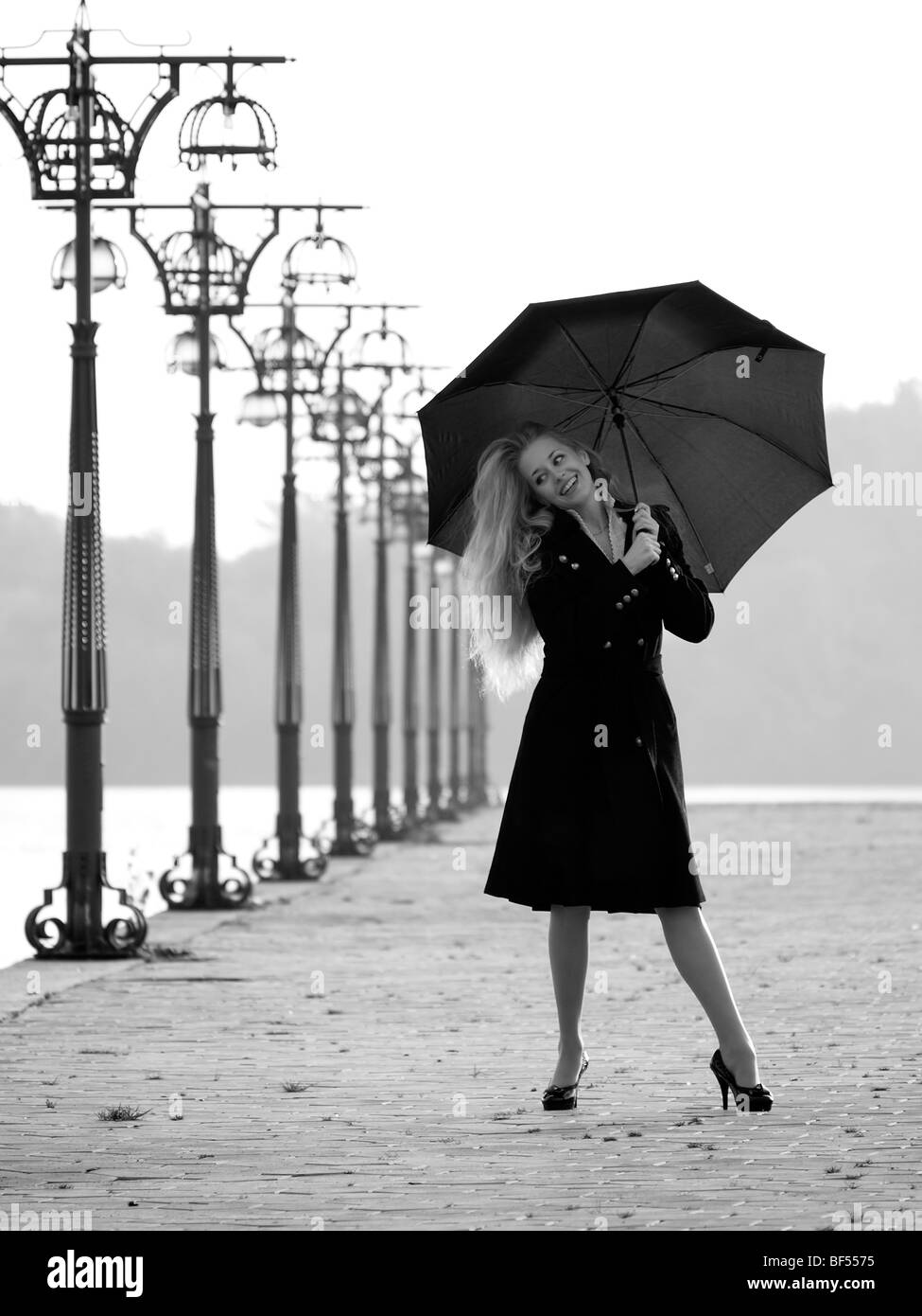 Belle blonde femme avec parapluie sur la promenade Banque D'Images