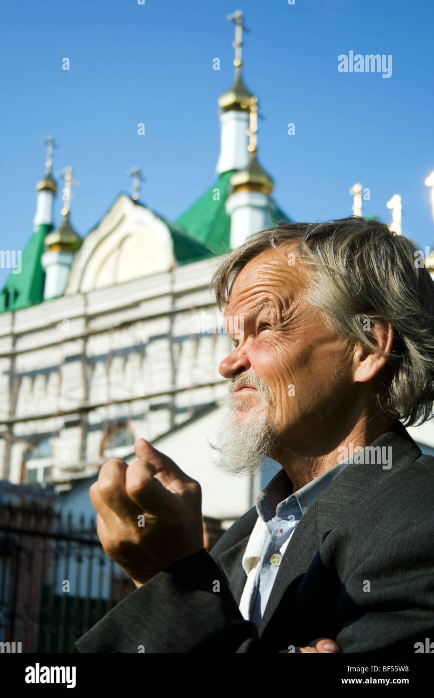 Vieil homme triste contre une cathédrale. Banque D'Images