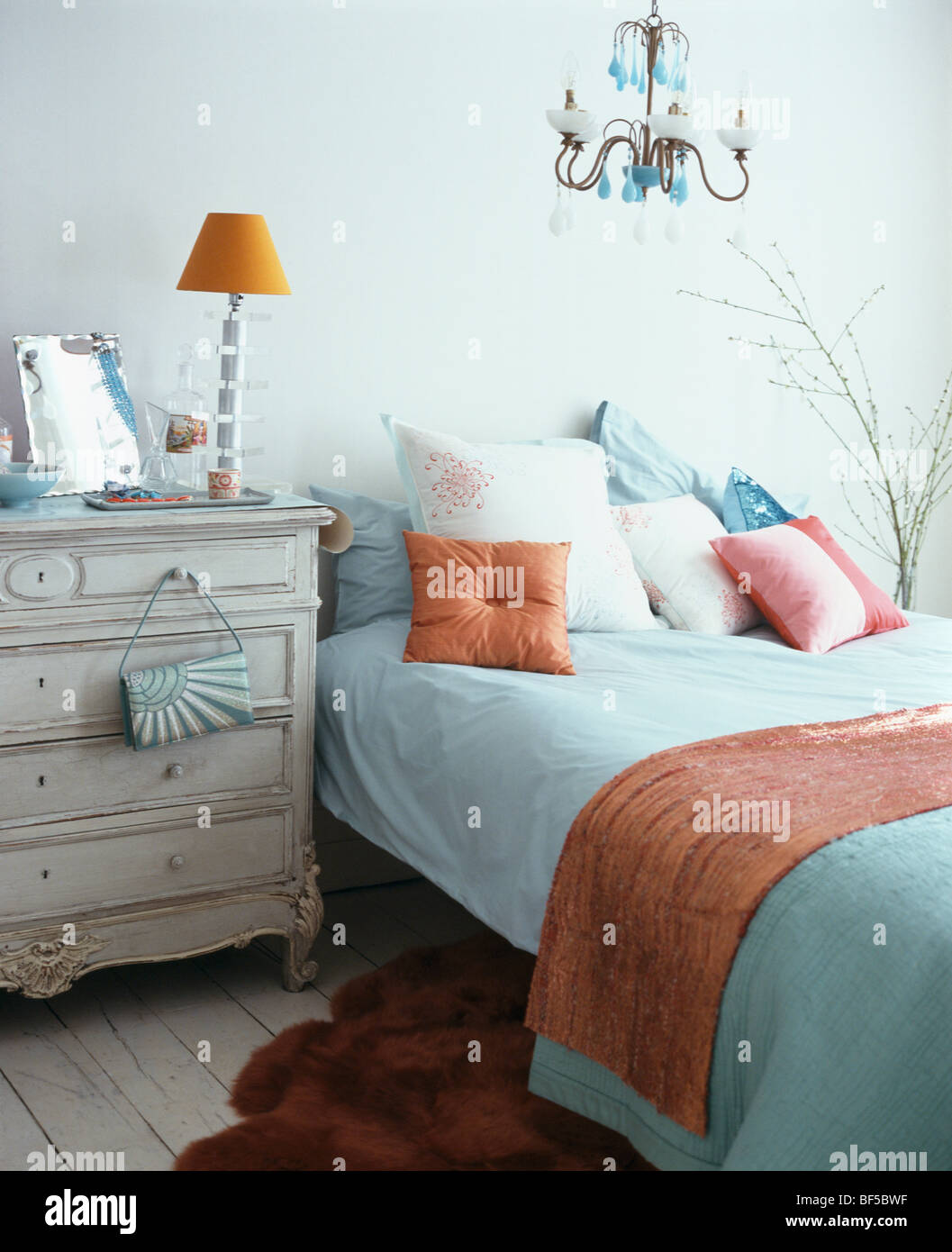 Lampe orange sur la poitrine crème-de-tiroirs à côté de lit avec ... Lampe orange sur la poitrine crème-de-tiroirs à côté de lit avec ...