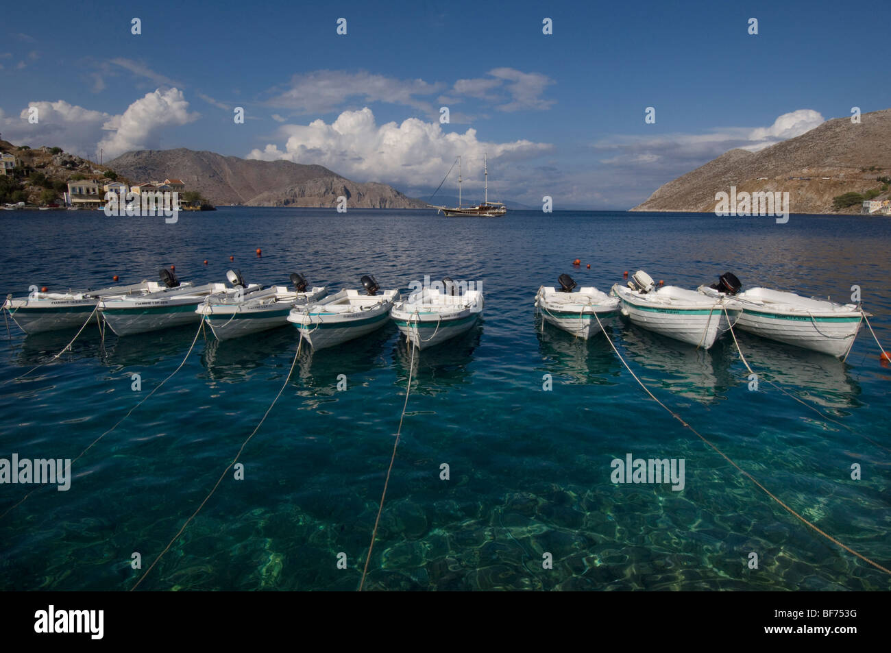 Une rangée de huit petits bateaux amarrés dans le port de Symi Town, Grèce. Banque D'Images