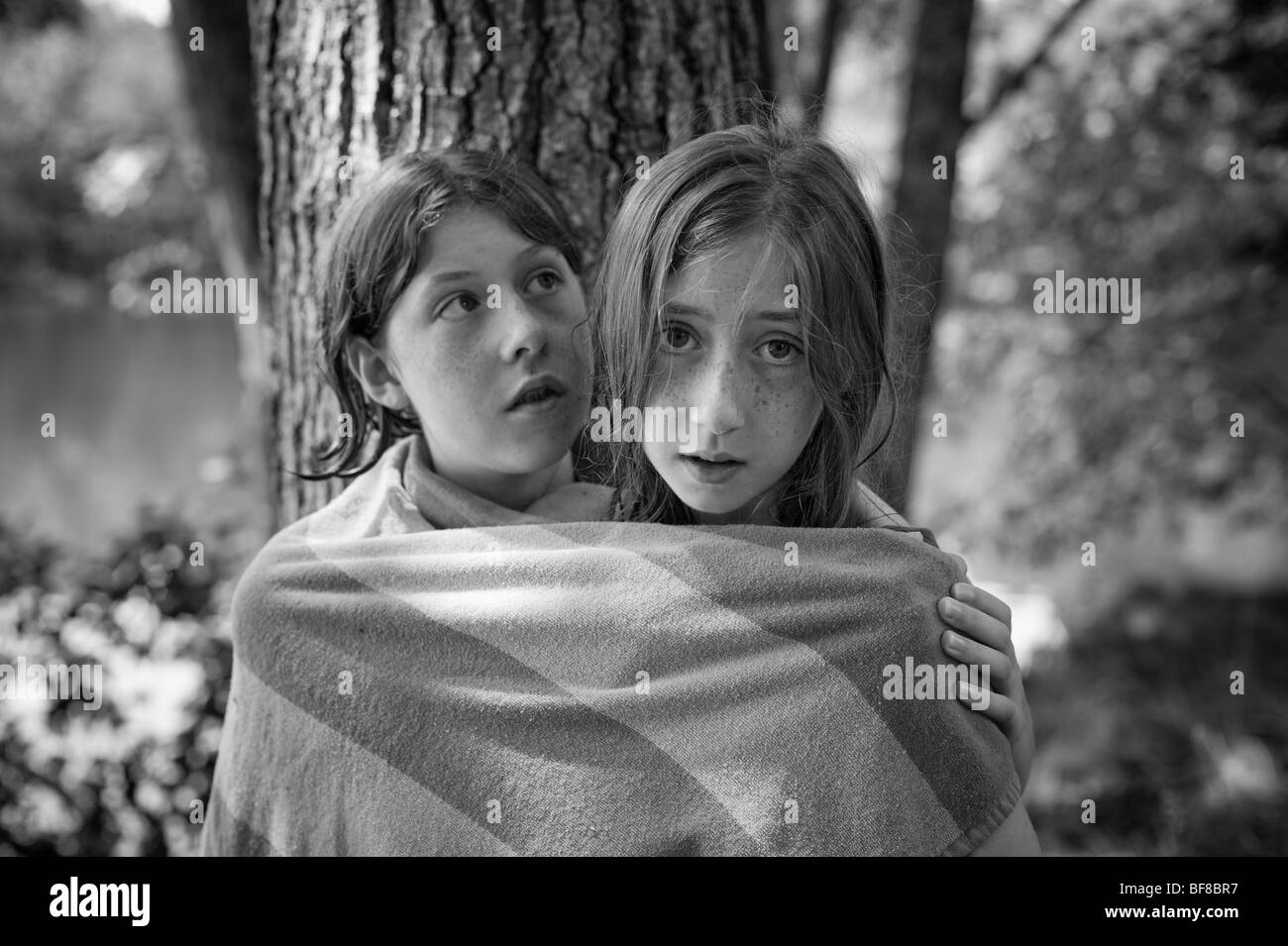 Photographie en noir et blanc de deux filles debout devant un arbre dans une serviette. Banque D'Images