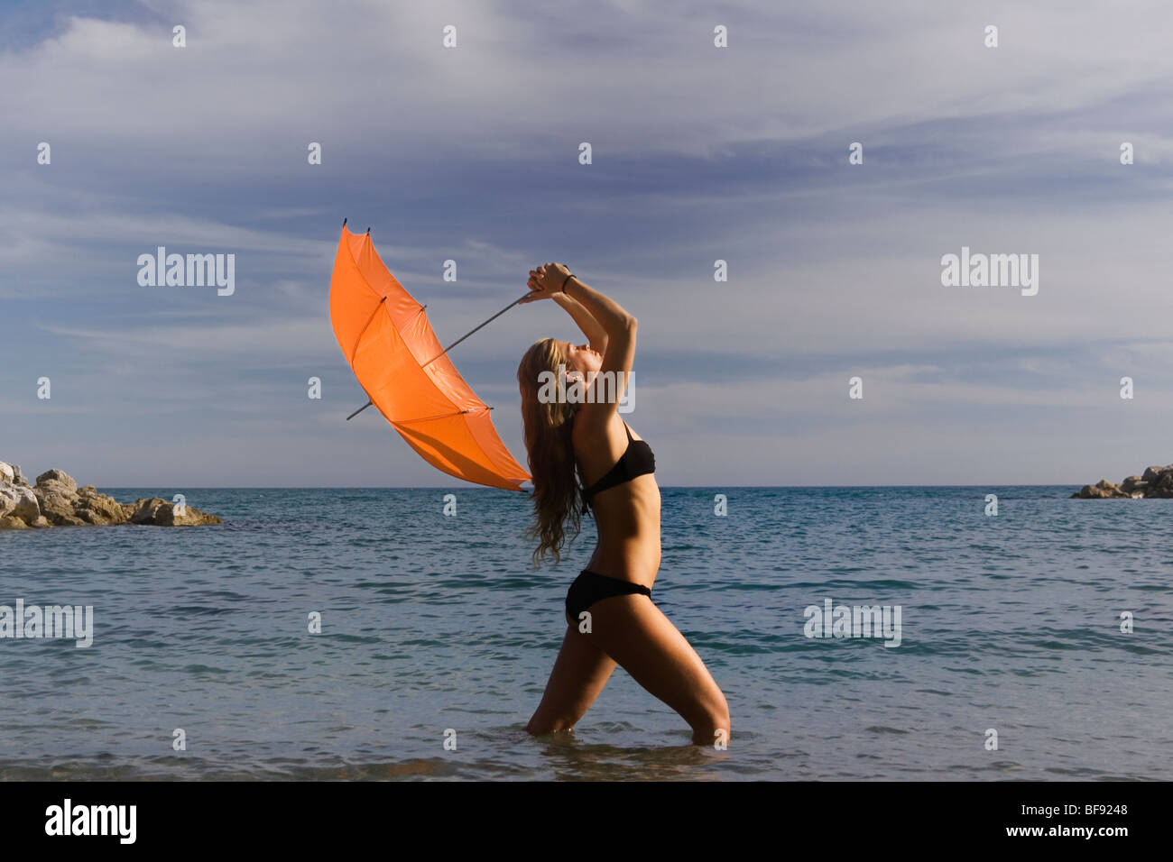 Woman standing in sea holding orange parasol contre ciel d'orage Photo  Stock - Alamy