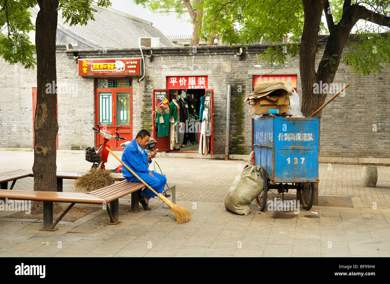 Un uniforme bleu en nettoyant la rue en faisant une pause et consultation des messages sur son téléphone portable, Beijing CN Banque D'Images