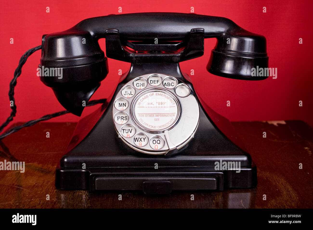 1940 téléphone bakélite contre un mur rouge. Banque D'Images