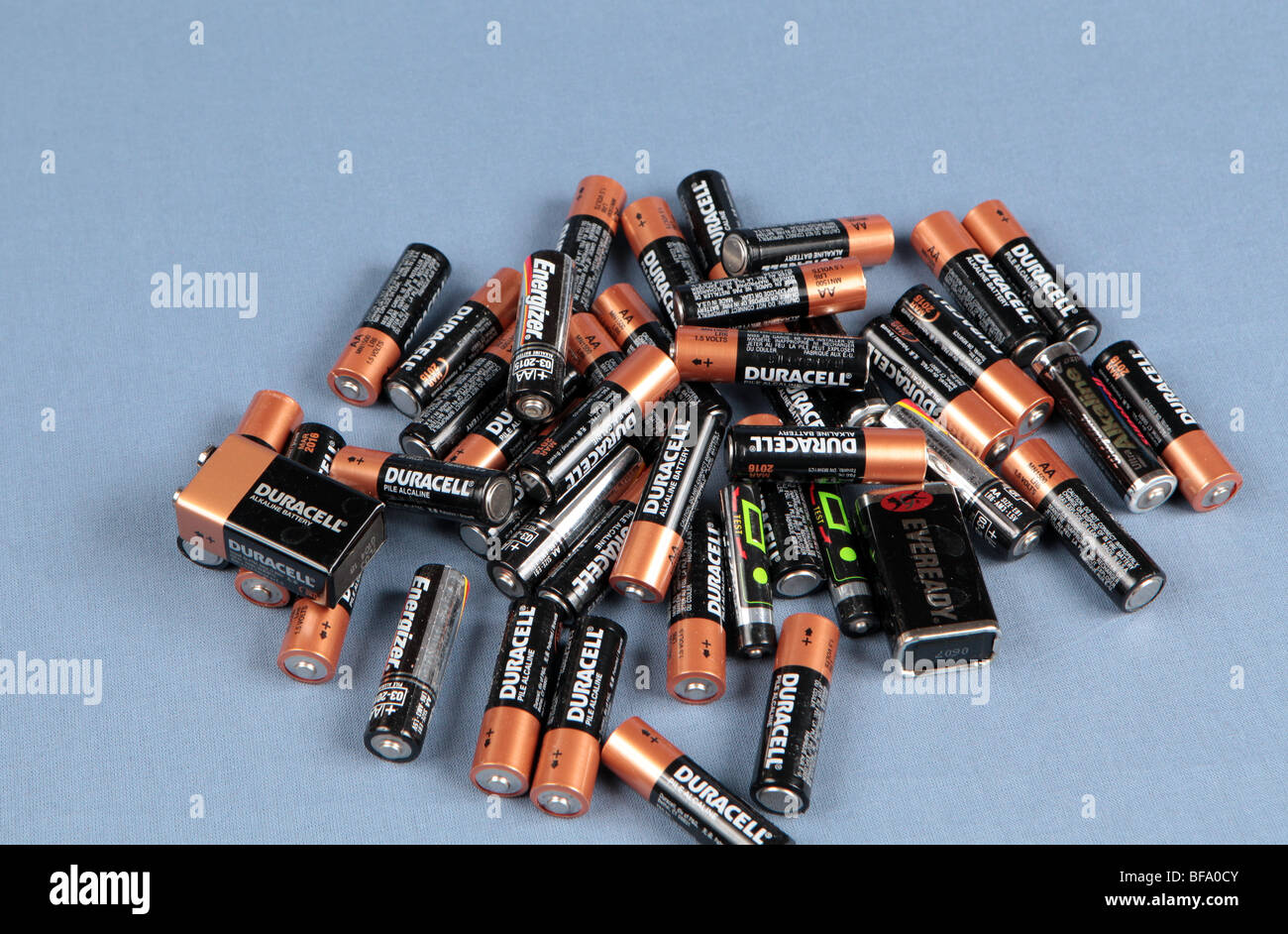 Une pile de piles AA empilés sur une table tourné sur un fond bleu. Les batteries prêt pour le recyclage. Banque D'Images