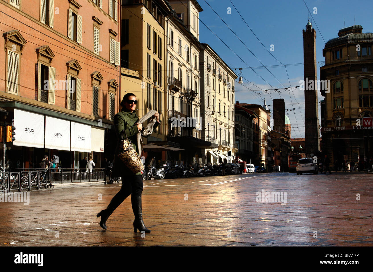 Femme traverse la rue Via Francesco Rizzoli avec la tour Asinelli, derrière l'un des deux tours de Bologne à Bologne Italie Banque D'Images