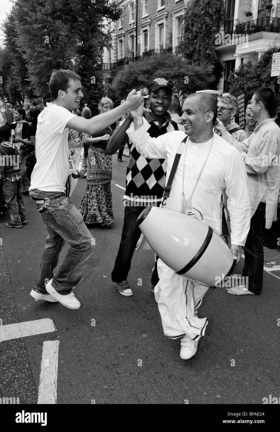 Les dévots de Krishna Hare danse avec Carnival reverlers Westbourne Park Road à Notting Hill Carnival 2009 Banque D'Images