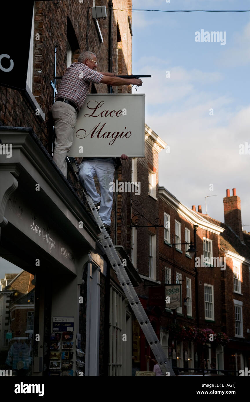 Deux hommes la pendaison d'un la boutique sign dans la ville historique de York en Angleterre Banque D'Images