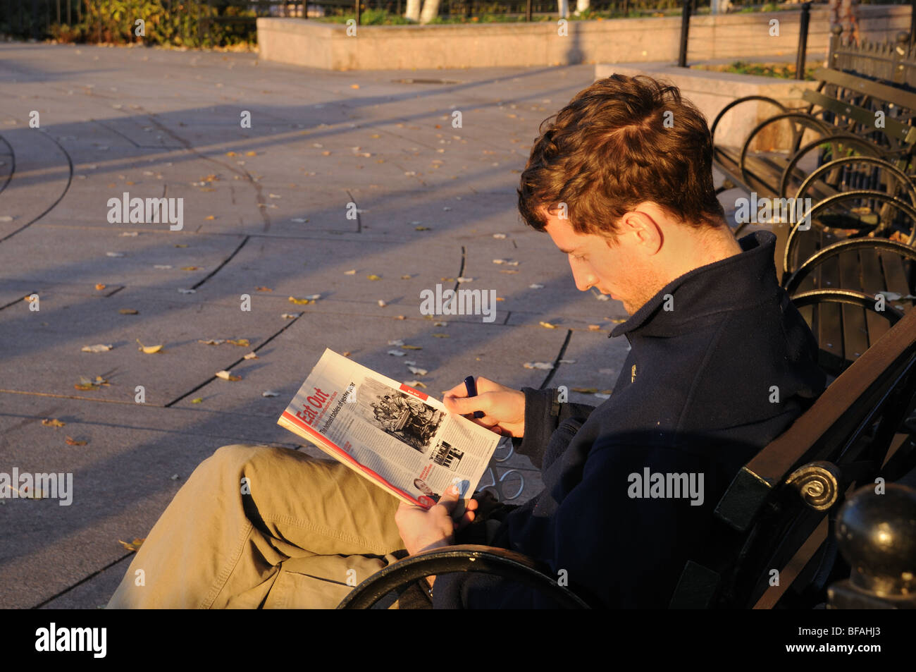 Un homme qui lit un magazine dans Battery Park City, un quartier de Manhattan. Banque D'Images