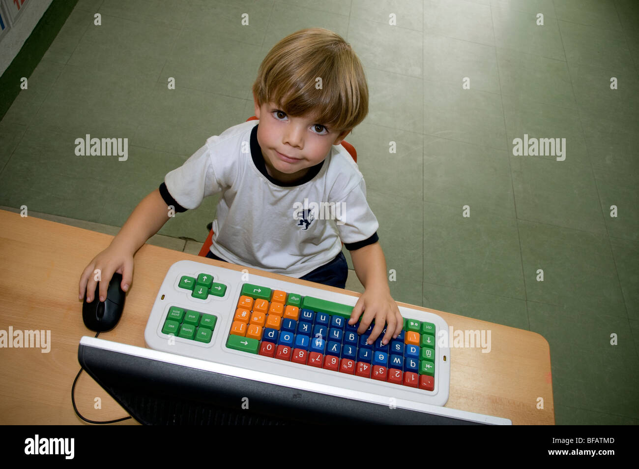 Le garçon lève les yeux de son ordinateur à l'école maternelle spécial Banque D'Images