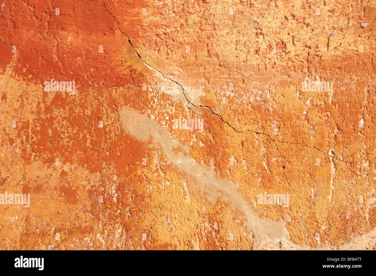Mur de platère peint en jaune orange avec surface de peinture vieillissante, texture rustique Banque D'Images