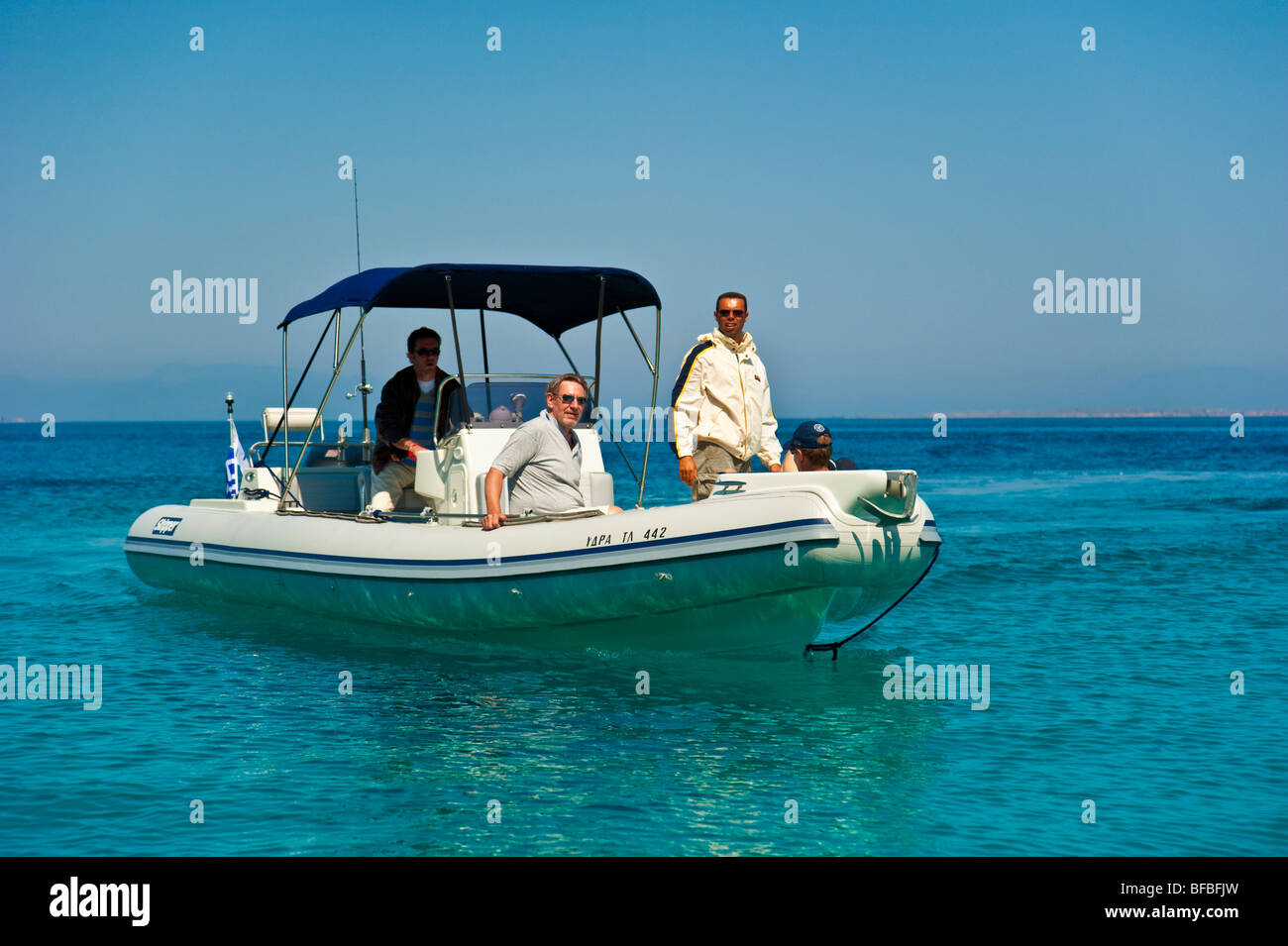 Trois hommes sur le bateau gonflable dans l'eau turquoise, le Golf Saronique, Grèce Banque D'Images